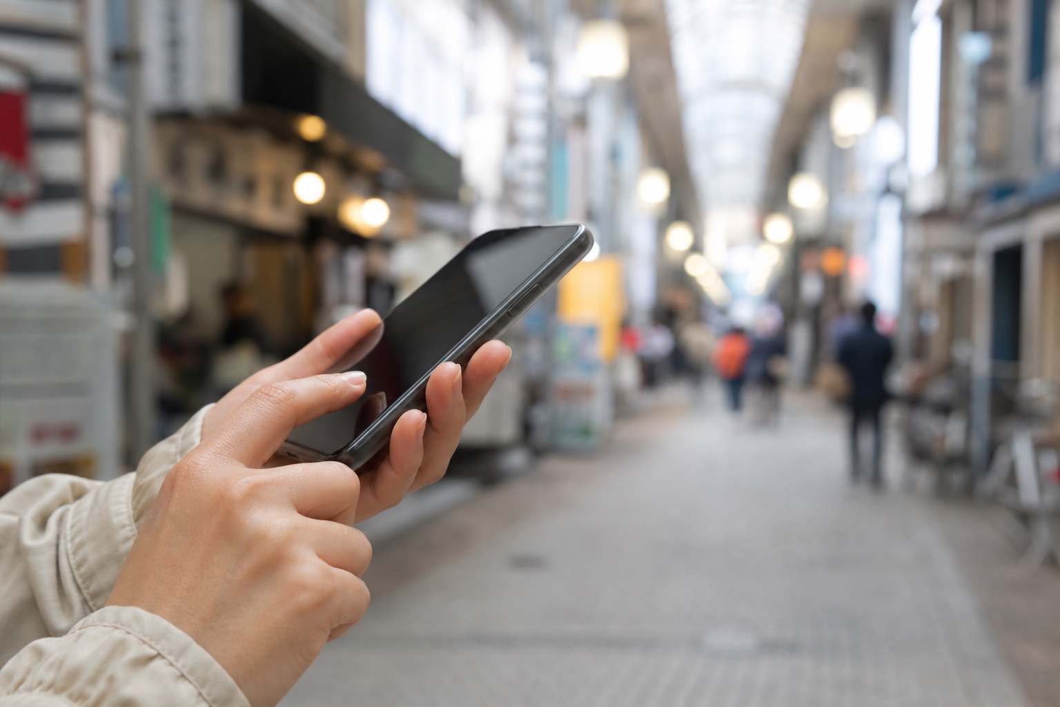 商店街でスマートフォンを見る人の手元
